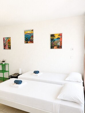 A hotel room with two beds, a green side table, and three paintings on the wall. - Le Thiers Azur AP4520 by Riviera Holiday Homes (Nice)