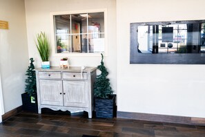 Un área de recepción con un mueble de madera, una planta en maceta y un pequeño árbol de Navidad.