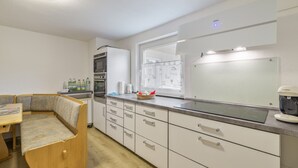 A compact kitchen with white cabinets, a built-in oven, and a coffee machine.
