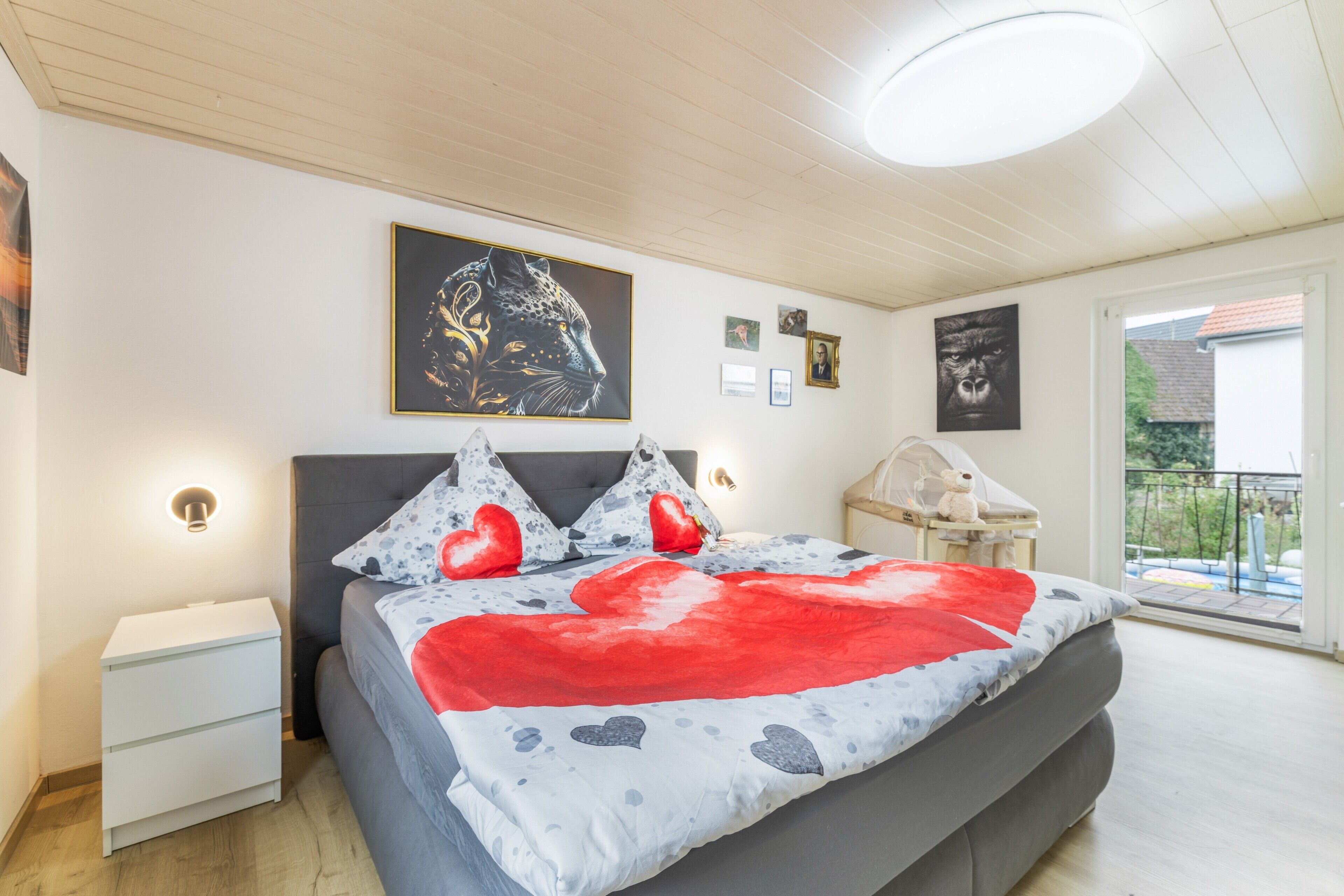 Un dormitorio con cama, mesitas de noche, una ventana con vistas y decoración en la pared.