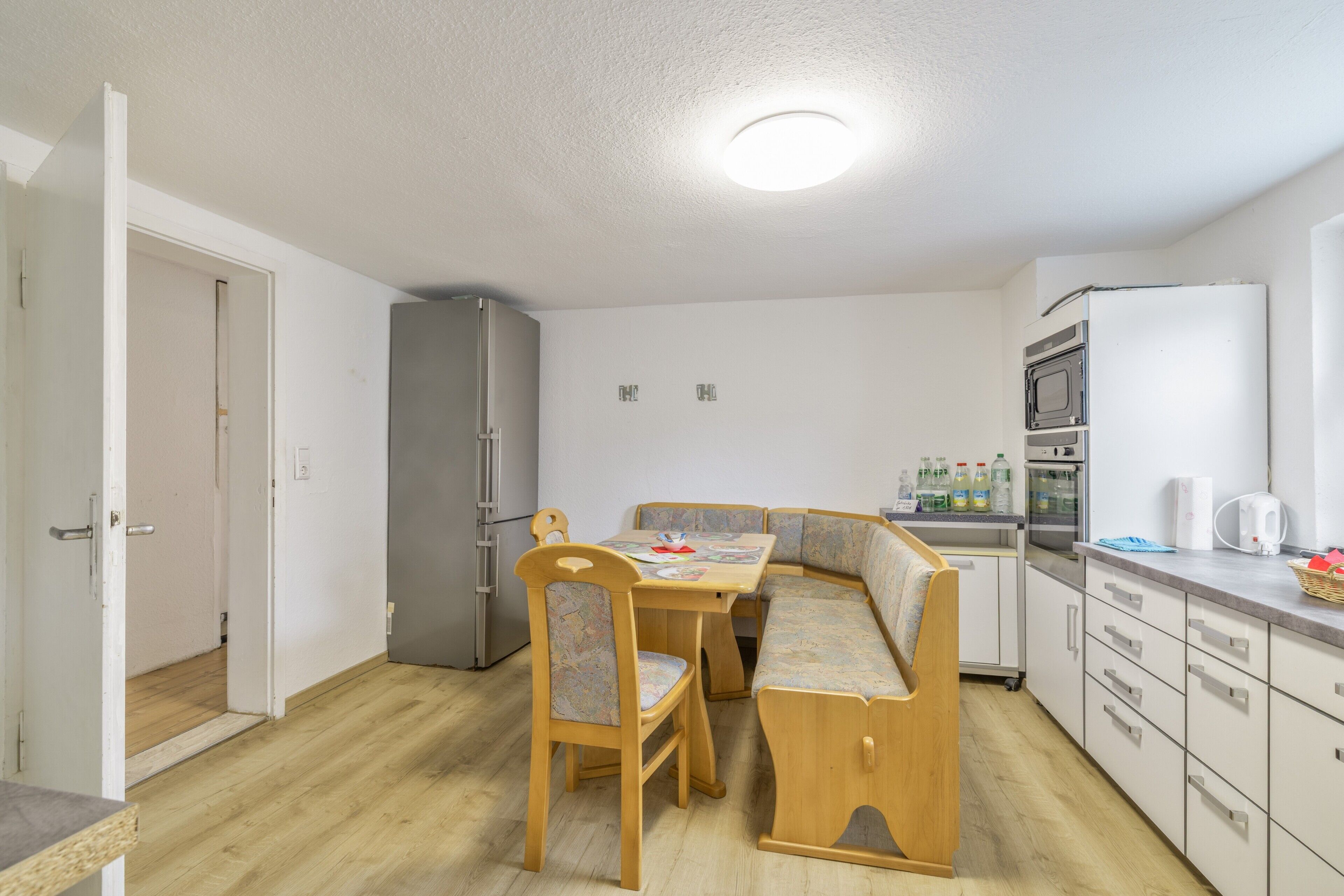 Cocina compacta con una mesa de comedor, sillas, un refrigerador y un microondas.