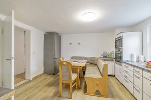 A compact kitchen with a dining table, chairs, a refrigerator, and a microwave. - Apartment 'Am Fuße des Zoller' with Balcony and Wi-Fi (Bisingen)