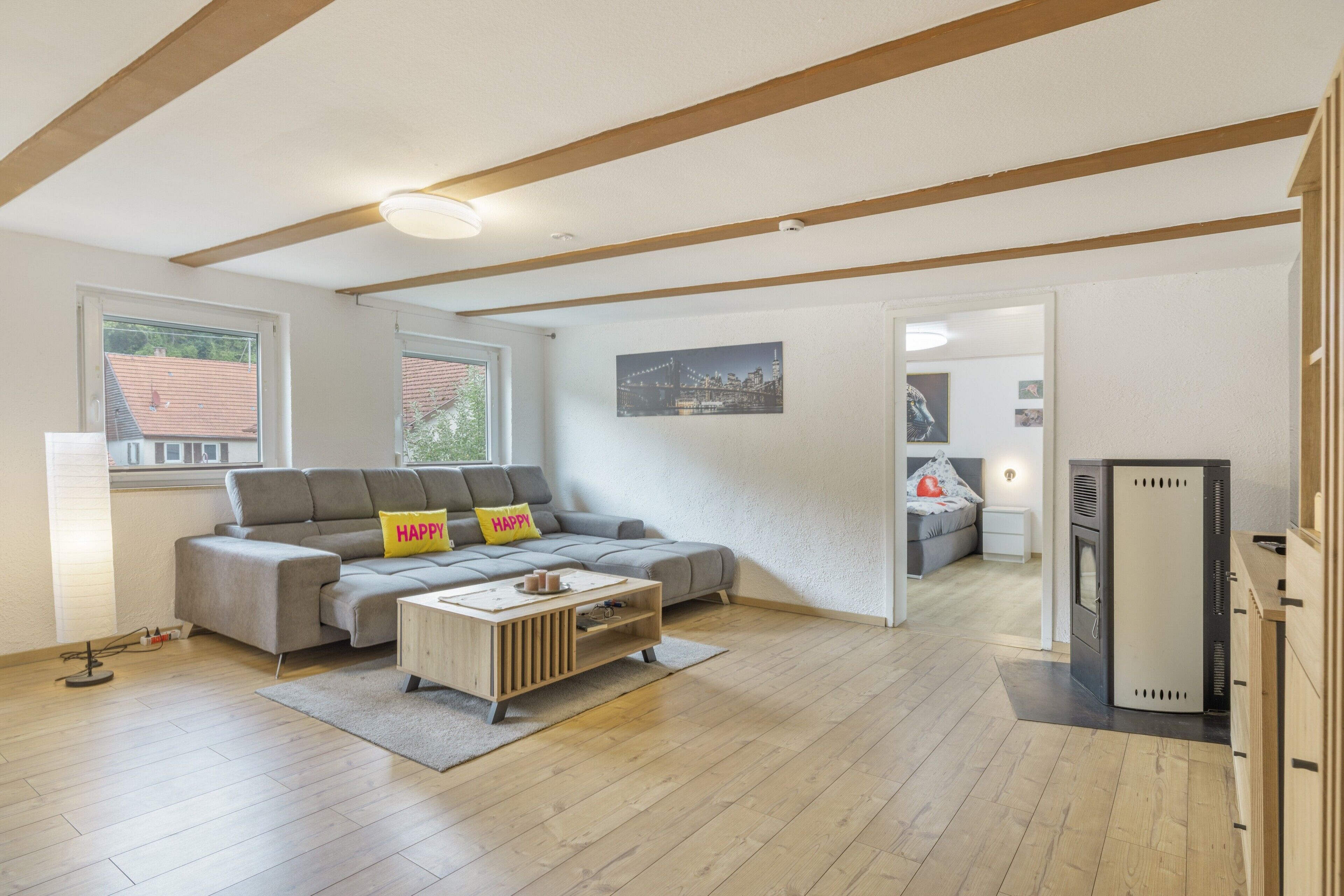 A modern living room with a grey sofa, a wooden coffee table, and a cityscape painting on the wall.