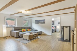 A modern living room with a grey sofa, a wooden coffee table, and a cityscape painting on the wall. - Apartment 'Am Fuße des Zoller' with Balcony and Wi-Fi (Bisingen)