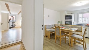 A compact kitchen with a dining area, wooden furniture, and a built-in oven.