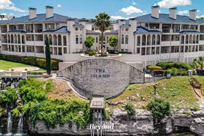 Un gran hotel de varios pisos con un patio central, una cascada y un cartel llamativo que dice "The Island".