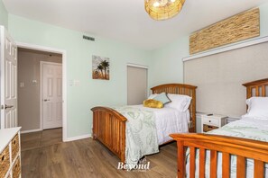 A bedroom with a bed, bedside tables, a door, and a wall-mounted light fixture. - Villa 3102 - Chillin' on Lake Time (Lago Vista)
