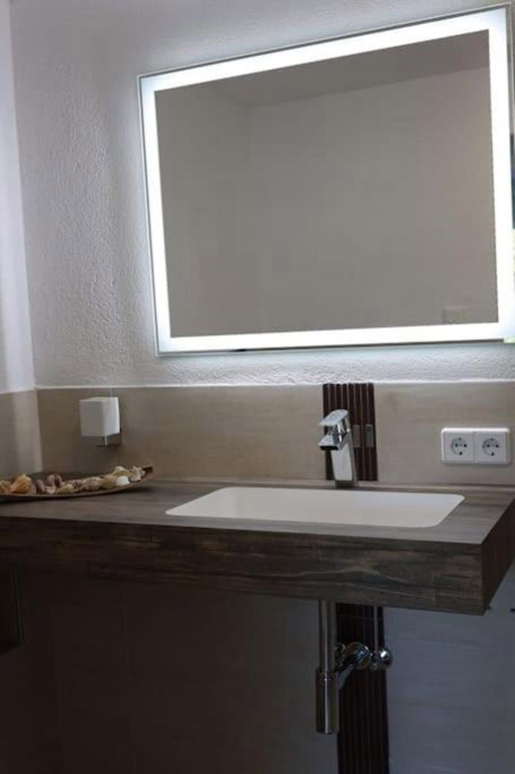 Une salle de bain avec un grand miroir, un lavabo et un porte-serviettes.