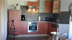 A compact kitchen with a built-in oven, a coffee maker, and a wine glass on a tray. - Rebstock Apartment at the Lahmer August Winery (Kretzschau)