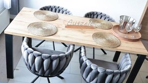 A dining table with four woven placemats, a wooden sign with text, and a set of glasses and a metal pitcher on a tray. - Rebstock Apartment at the Lahmer August Winery (Kretzschau)