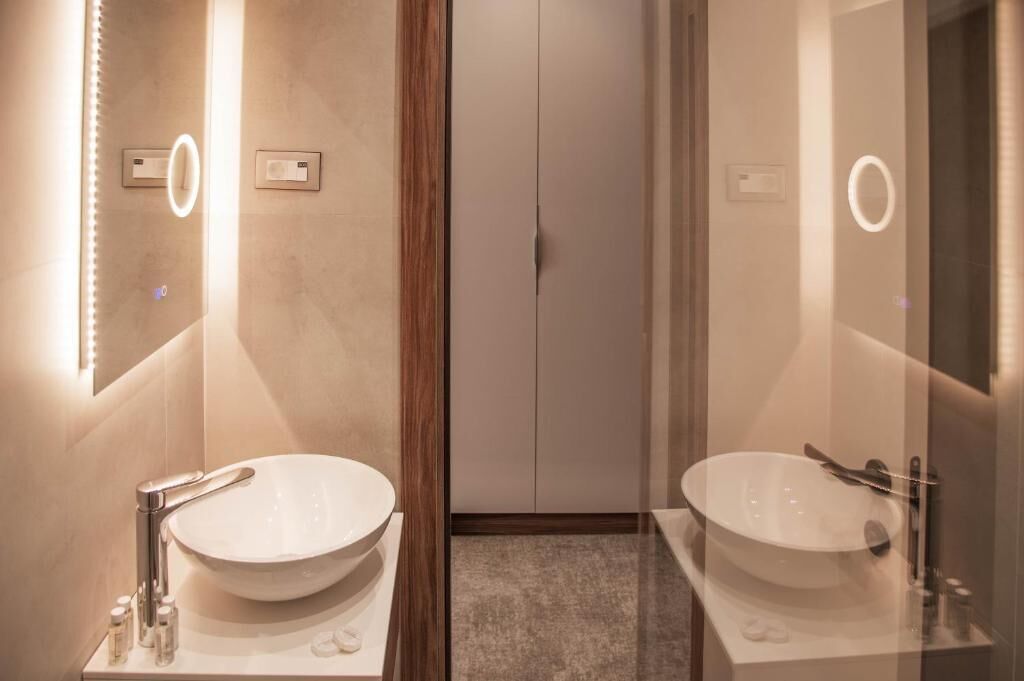 Un baño moderno con dos lavamanos grandes, un espejo y una puerta con pomo.