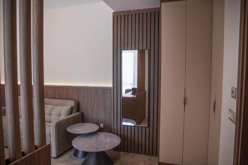Una habitación moderna con sofá, una mesita redonda, armario y espejo.