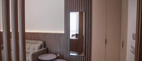A modern room with a sofa, a small round table, a wardrobe, and a mirror.