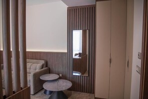 A modern room with a sofa, a small round table, a wardrobe, and a mirror. - Hotel Onogošt (Nikšić)