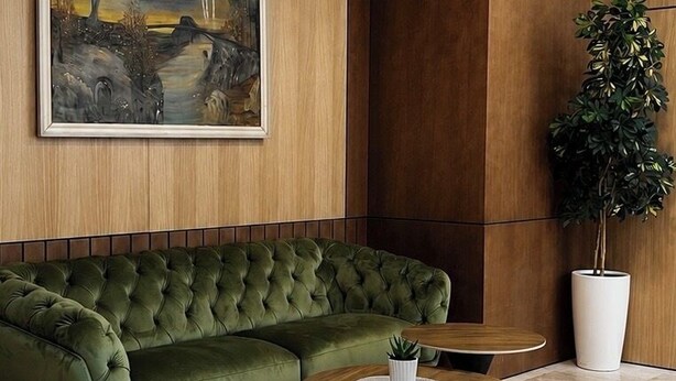 A modern living room with a green sofa, a painting, a potted plant, and a coffee table. - Hotel Onogošt (Nikšić)