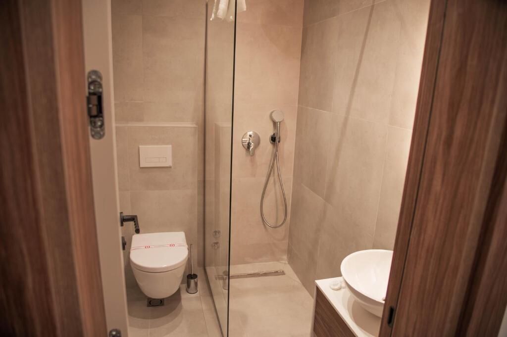 A modern bathroom with a glass-enclosed shower, a toilet, and a bidet.