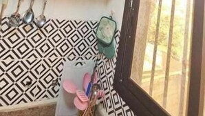 Eine Küche mit einem schwarzen Schrank, einem Fenster mit Gitterstäben und einer gemusterten Spritzschutzwand.