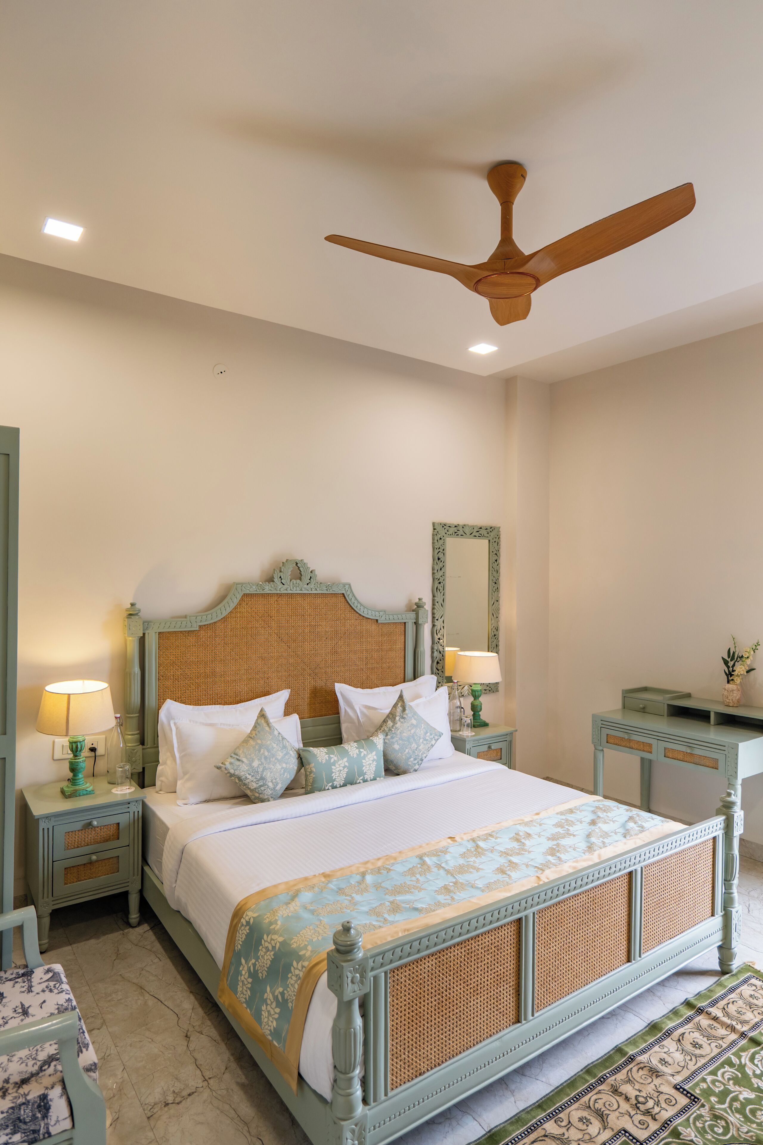 A bedroom with a bed, two bedside tables, a ceiling fan, a mirror, and a nightstand.