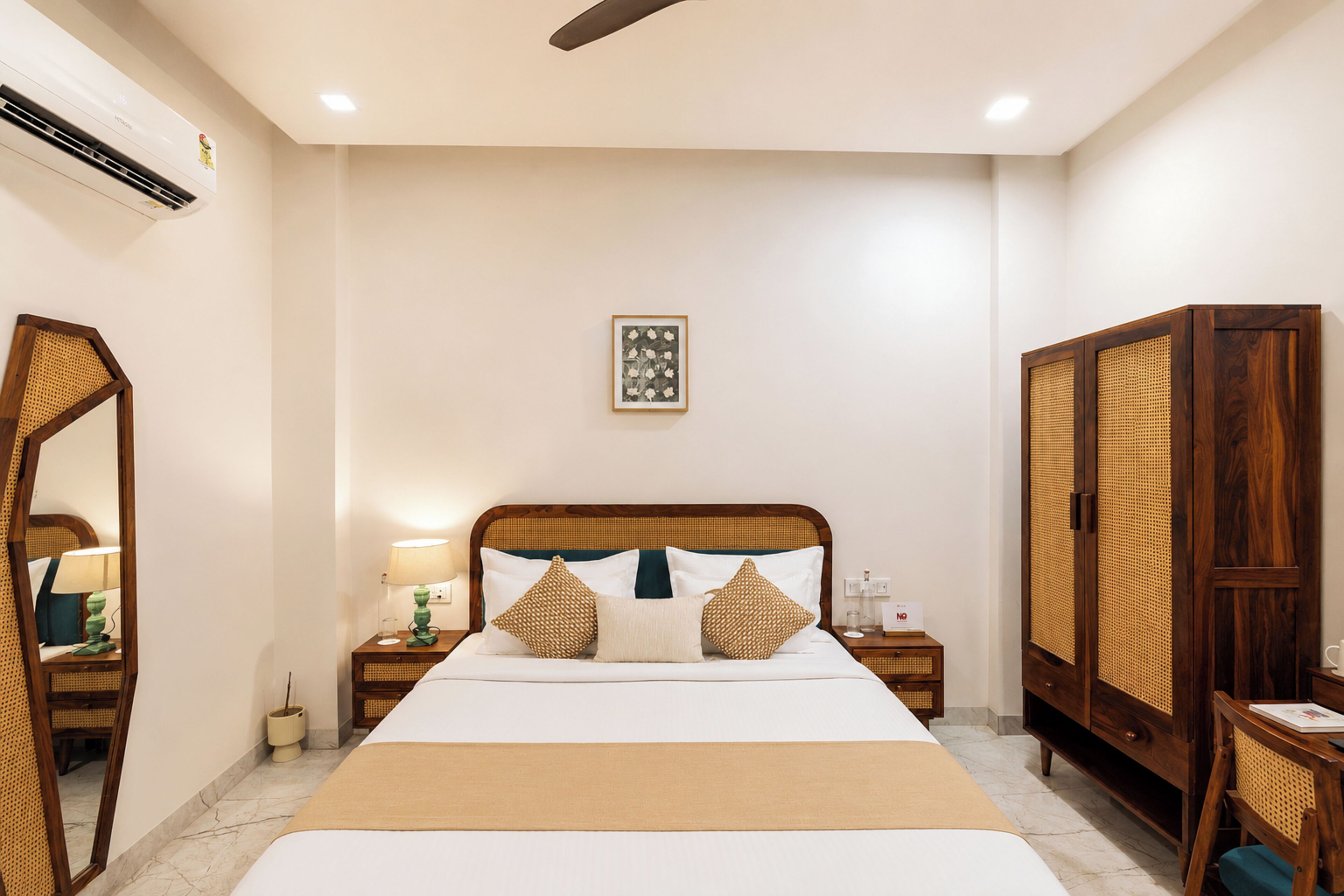 A hotel room with a bed, bedside tables, a mirror, a wardrobe, and a framed picture on the wall.