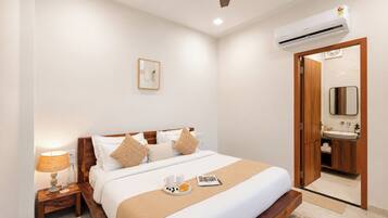 A hotel room with a bed, bedside table, lamp, and a bathroom with a mirror and sink.