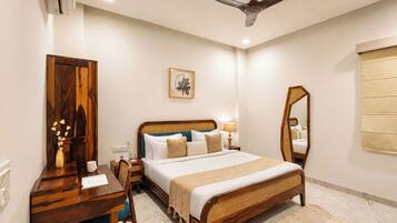 A bedroom with a bed, bedside table, lamp, mirror, and a ceiling fan.