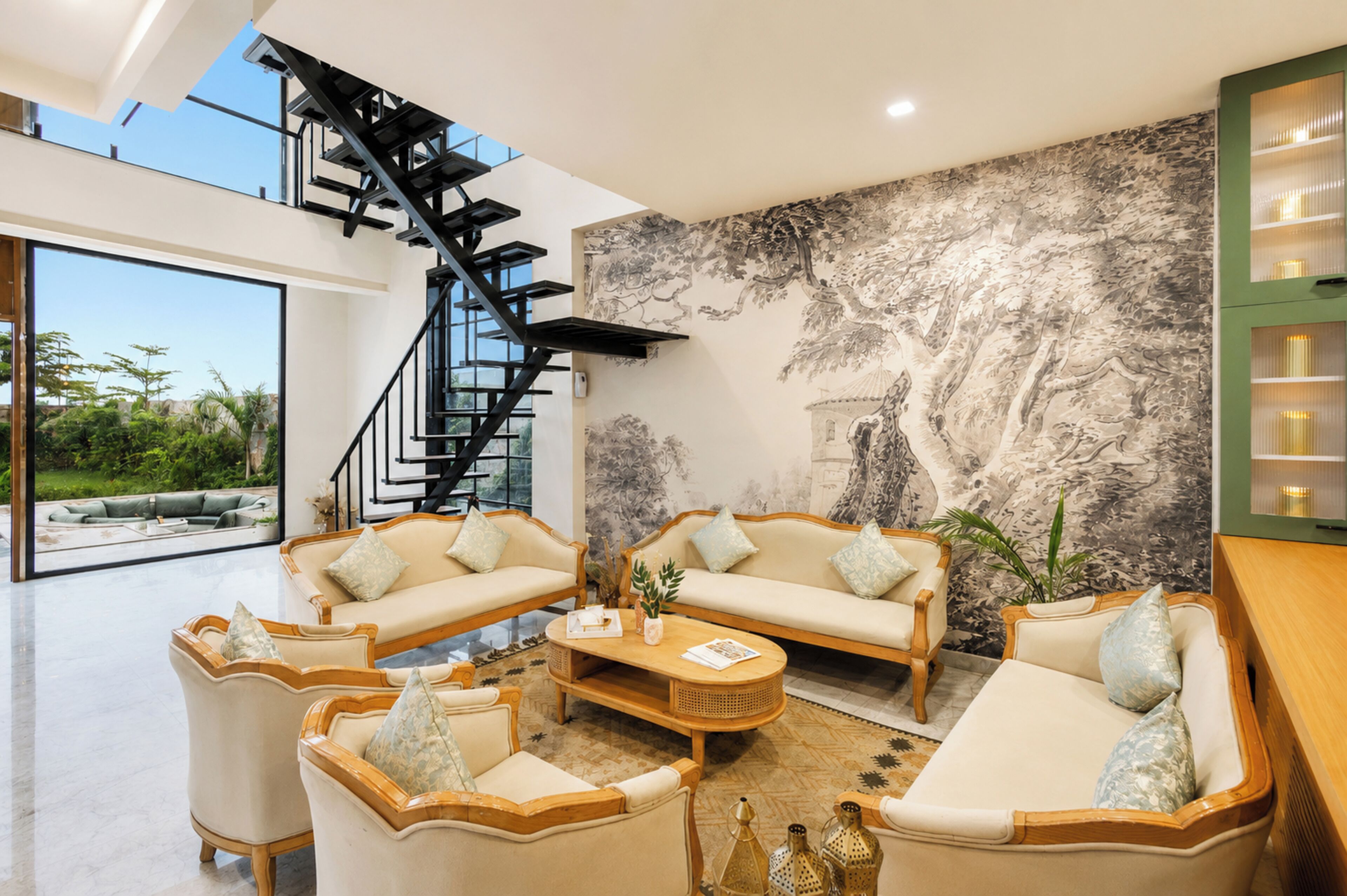 En moderne stue med trappe, to sofaer, et sofabord og et stort mural.
