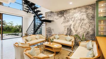 En moderne stue med trappe, to sofaer, et sofabord og et stort mural.
