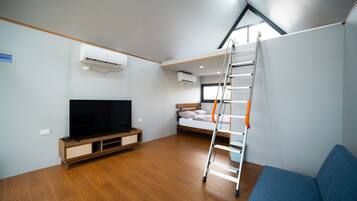 Een kleine kamer met televisie, stapelbed, ladder en ingebouwde airconditioning.