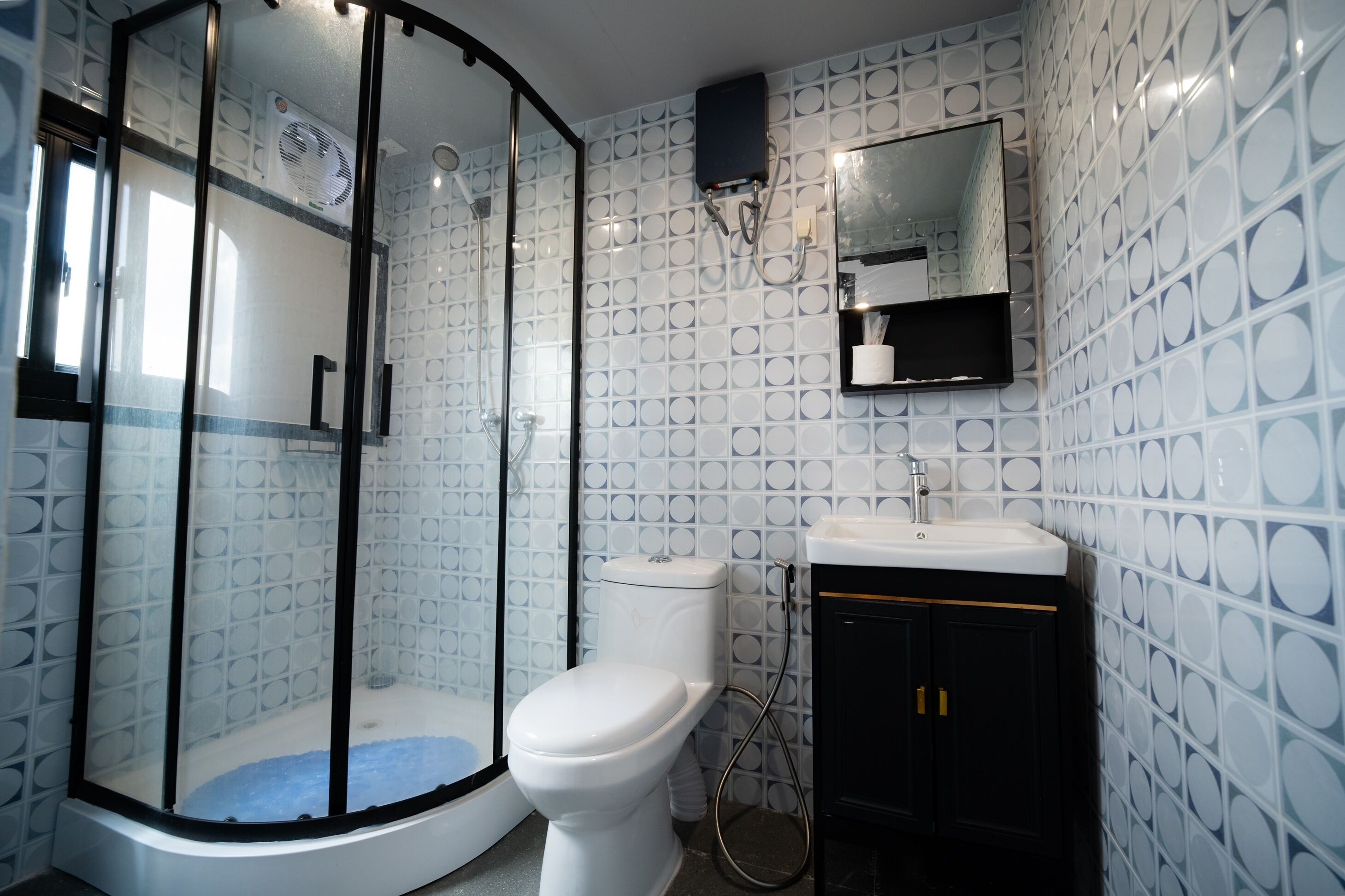 Een badkamer met een douchecabine van glas, toilet en wastafel met spiegel erboven.
