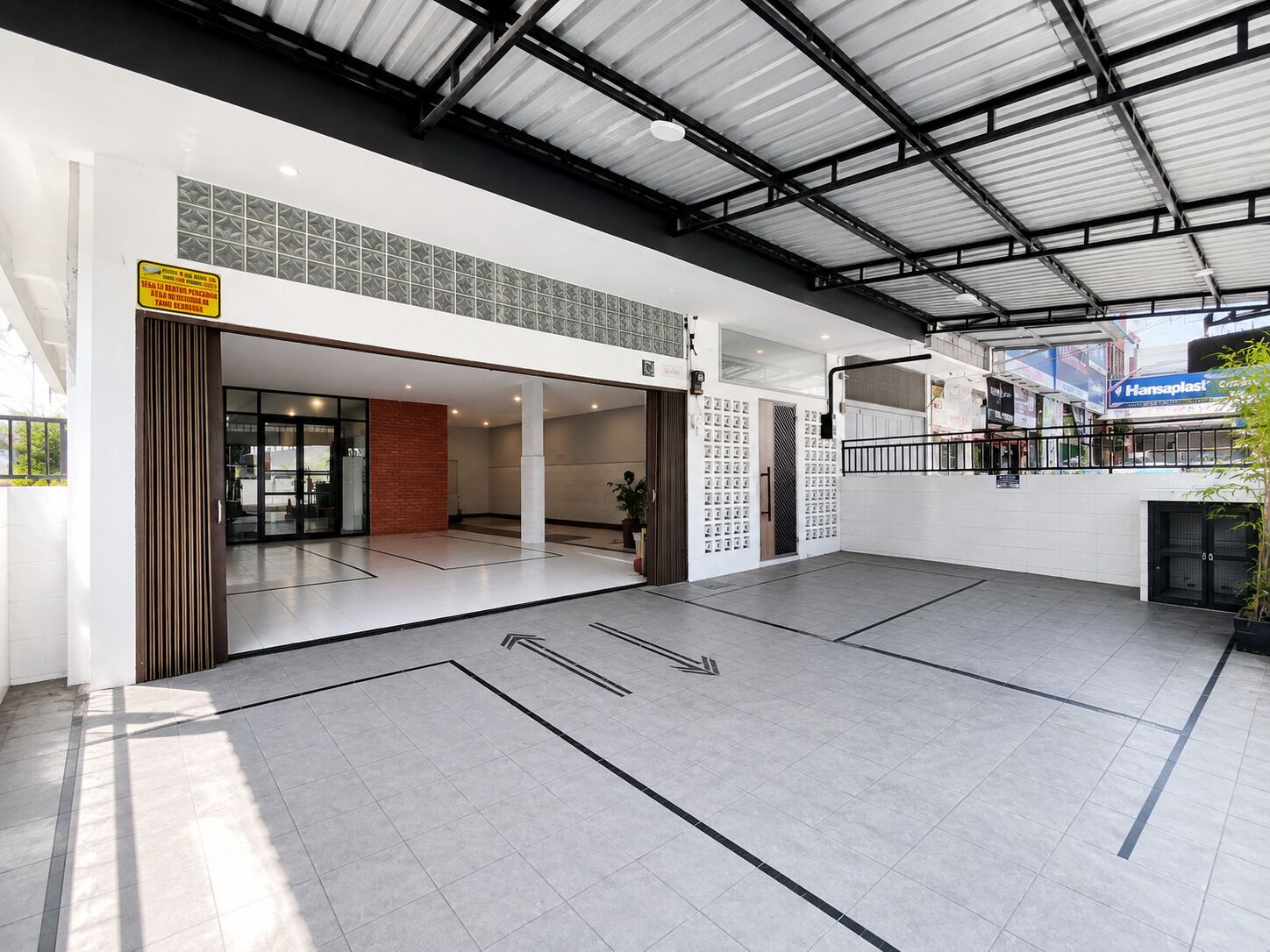 A spacious indoor area with a high ceiling, tiled flooring, and directional arrows on the floor.