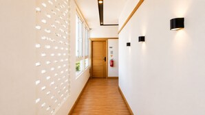 Un pasillo con suelo de madera, paredes blancas y una puerta con la etiqueta '3A1'.
