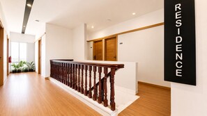Un interior residencial moderno con una escalera de madera, una pared blanca con un cartel que dice 'RESIDENCE' y una puerta marcada con el número 309.
