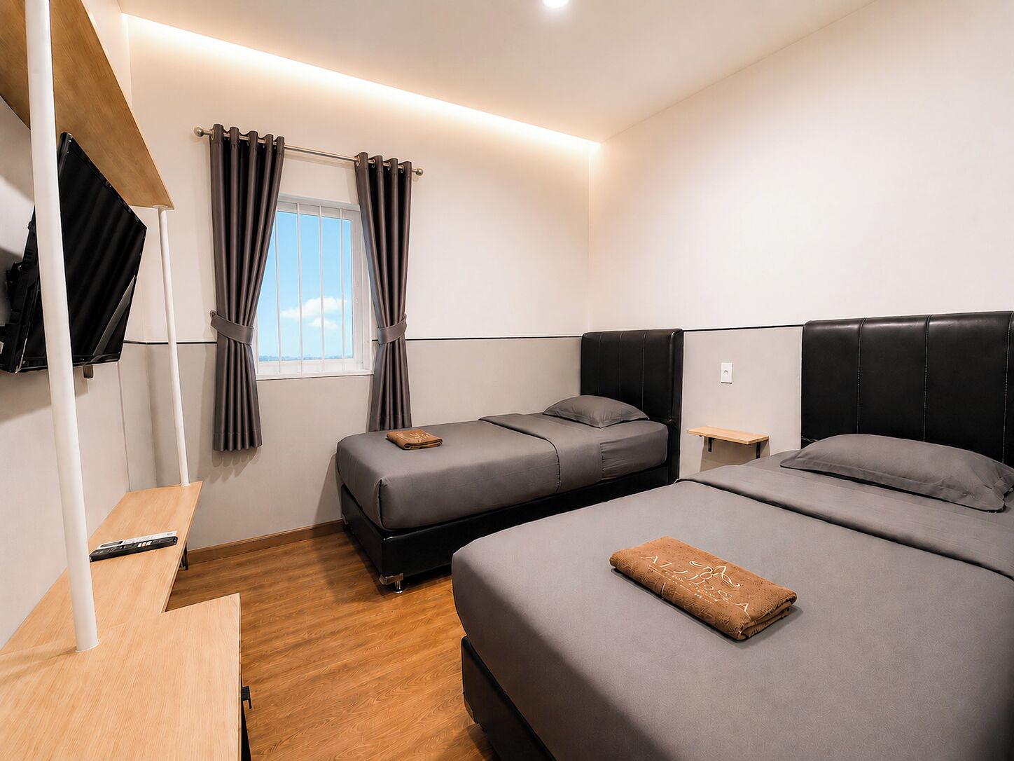 Une chambre d’hôtel avec deux lits, un bureau, une télévision et une fenêtre avec des rideaux.
