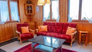 Et hyggeligt rum med trævægge, en rød sofa, et glasbord og et træskab med en telefon.
