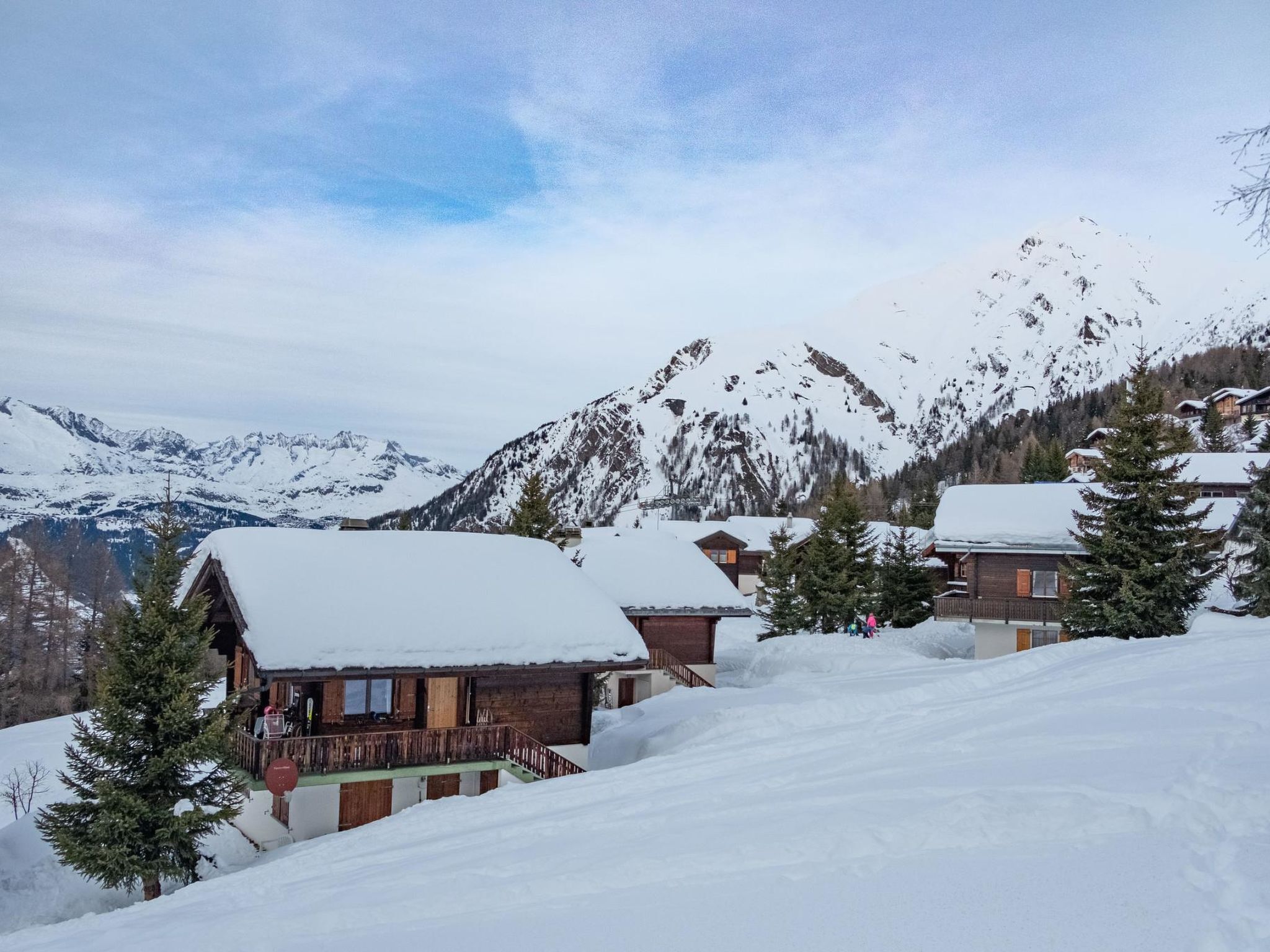 A snow-covered mountain village with wooden cabins and a ski slope.