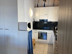 A modern kitchen with white cabinetry, a built-in oven, and a black countertop. - Chalet Lalula Appartement/Fewo, Dusche, WC Appartement/Fewo, Dusche, WC by Interhome (Rosswald)