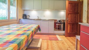 Quarto compacto com cama, cozinha compacta e teto de madeira.
