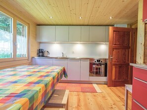Ein gemütlicher Raum mit Bett, Küchenzeile und Holzboden.