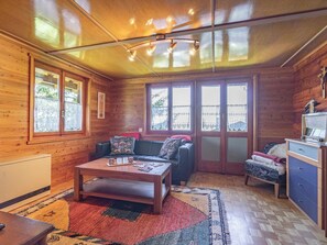 Ein gemütliches Blockhaus-Interieur mit Holzausstattung, einer Couch, einem Couchtisch und einer kleinen Küchenzeile.