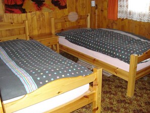 Two wooden bunk beds with a patterned bedspread, a small bedside table, and a wall-mounted lamp. - Chalet Alphütte Appartement/Fewo, Dusche, WC 4-Bettwohnung Erdgeschoss by Interhome (Rosswald)