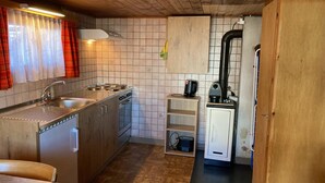 Pieni, käytännöllinen keittiö, jossa on kaasuliesi, pesuallas ja pieni jääkaappi.