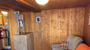 Tunnelmallinen huone, jossa on puuseinät, sohva, pieni pöytä ja kirjahylly.