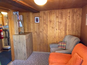 Et hyggeligt rum med trævægge, en sofa, et lille bord og en reol.