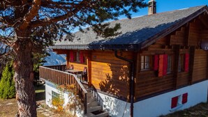 Una cabaña de madera con balcón, escaleras y vistas a la montaña.