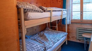 Dormitorio con literas, ventana y una mesita.