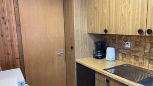 Eine kleine Küche mit Holzschränken, einer Kaffeemaschine und einem Spülbecken.