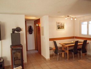 A dining area with a wooden table and chairs, a painting on the wall, and a television on a stand. - Fletschhorn EG 4-Bettwohnung, Dusche, WC 4-Bettwohnung by Interhome (Rosswald)