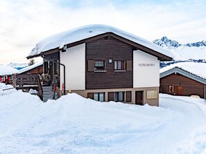 A two-story building with a ski lift and a mountain backdrop. - Fletschhorn EG 4-Bettwohnung, Dusche, WC 4-Bettwohnung by Interhome (Rosswald)