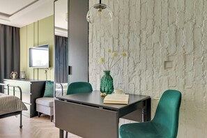 A modern living room with a dining area, a flat-screen TV, a green vase with flowers, and a book on the table. - Rezydencja Wintera 1B | River View (Gdańsk)