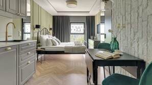 Moderni hotellihuone, jossa on sänky, työpöytä, tuoli, ruokapöytä ja näköala kaupunkiin.